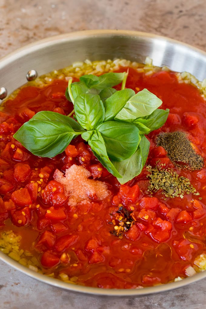 Diced tomatoes in a pan with olive oil and fresh basil.