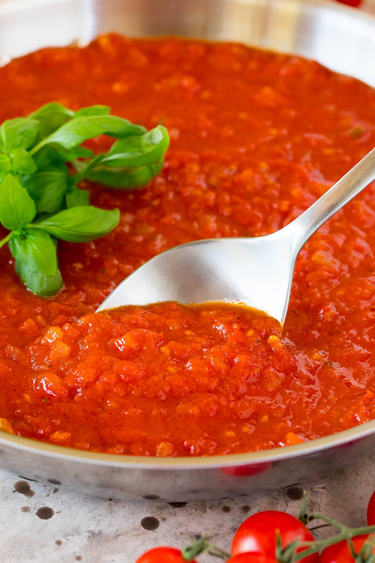 A serving spoon in a pan of homemade marinara sauce.