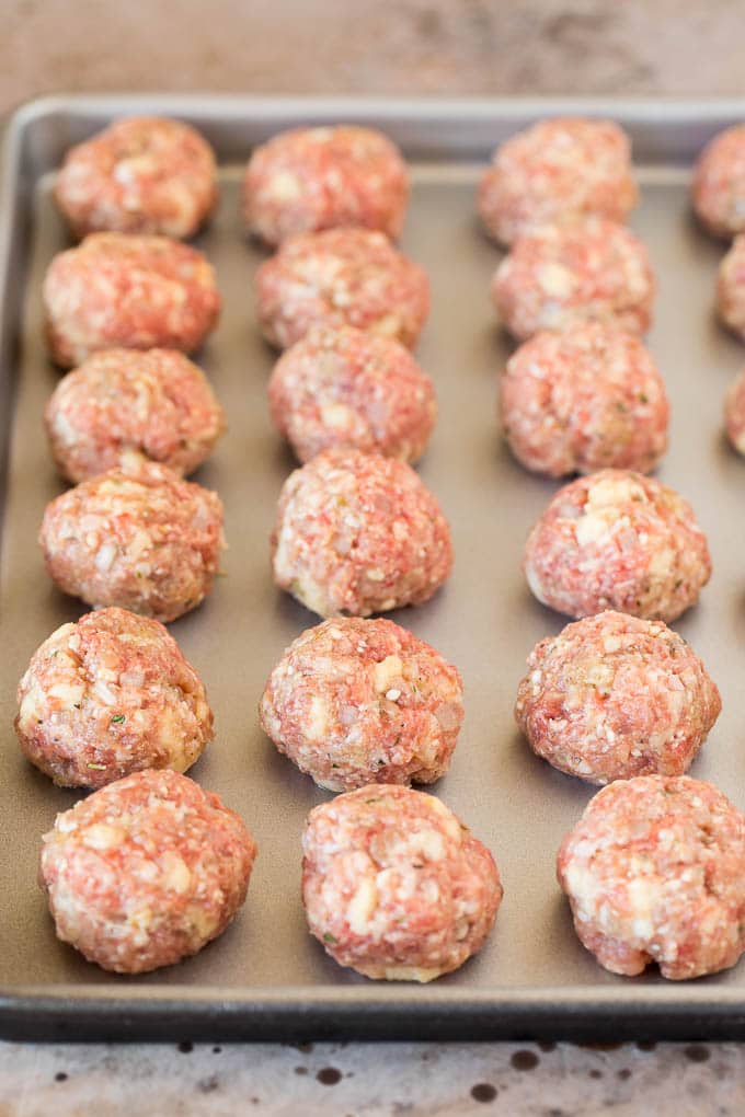 Raw balls of meat on a sheet pan.