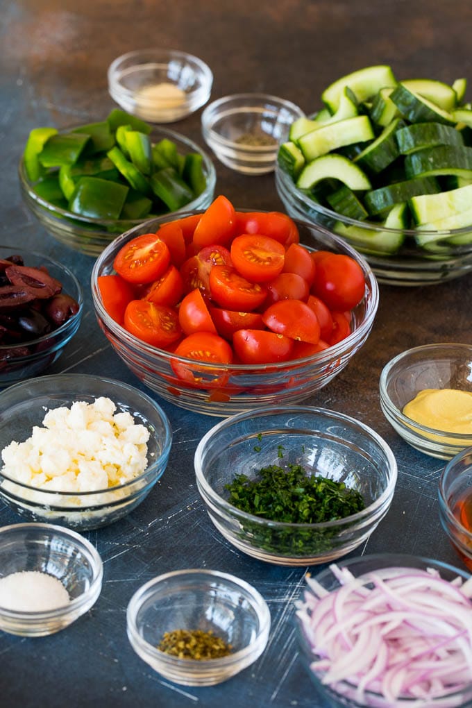 Bowls of vegetables, feta cheese and salad dressing ingredients.