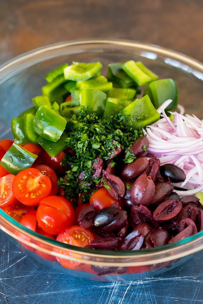 Cherry tomatoes, cucumbers, bell peppers and olives in a bowl.