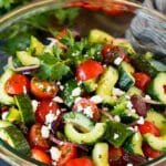 A bowl of Mediterranean salad with tomatoes, cucumbers, peppers and olives.