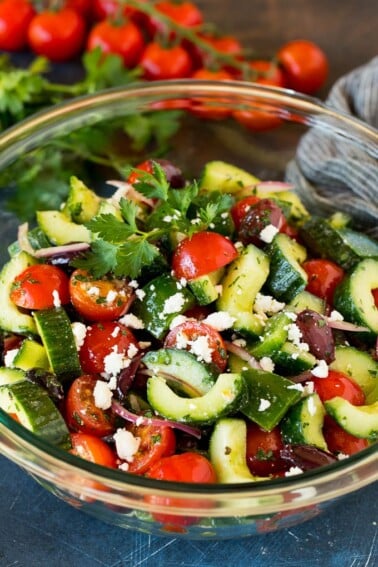 A bowl of Mediterranean salad with tomatoes, cucumbers, peppers and olives.