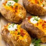 A pan of oven baked potatoes topped with sour cream, cheese and bacon.