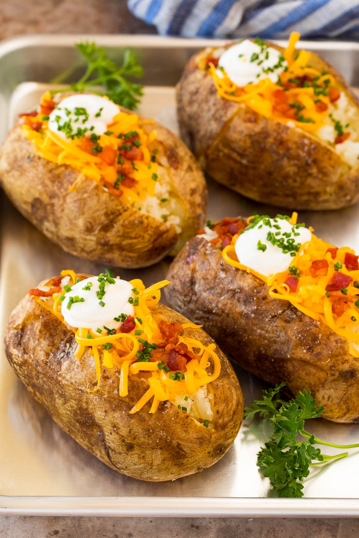 A pan of oven baked potatoes topped with sour cream, cheese and bacon.