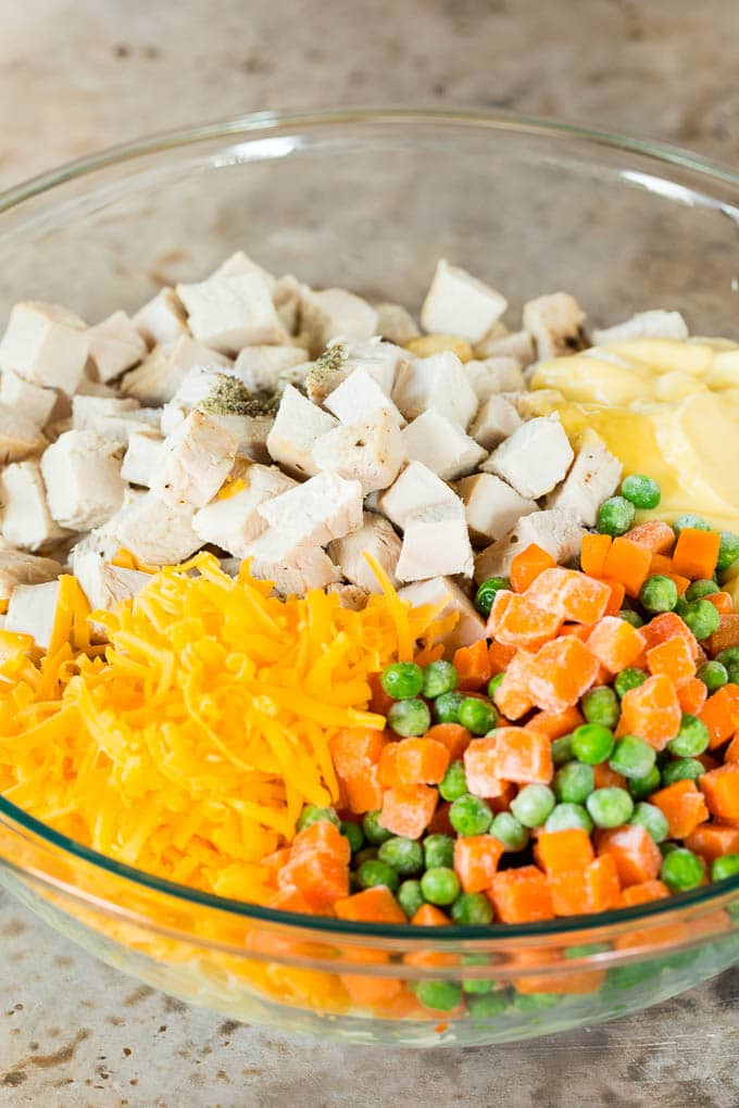 Turkey, pasta, frozen vegetables and cheese in a large bowl.