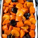 A casserole dish full of tzimmes that is garnished with orange zest.