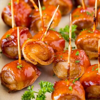 Bacon wrapped water chestnuts on a sheet pan, garnished with parsley.