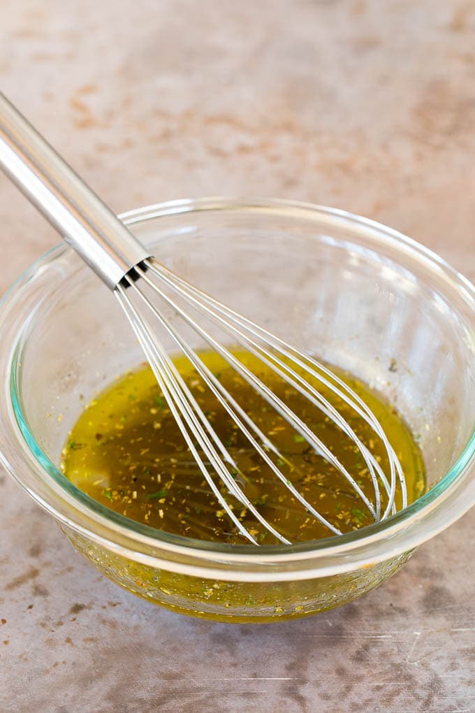 A bowl of homemade Italian dressing with a whisk in it.