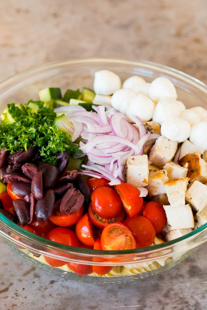 Chicken, vegetables and olives in a bowl with pasta.