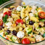 A bowl of chicken pasta salad with tomatoes, cucumbers and cheese.