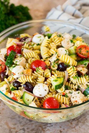 A bowl of chicken pasta salad with tomatoes, cucumbers and cheese.