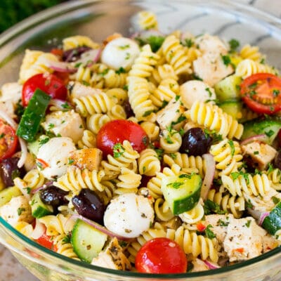 A bowl of chicken pasta salad with tomatoes, cucumbers and cheese.