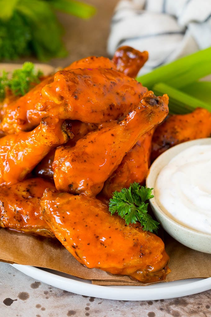 Air fryer chicken wings coated in buffalo sauce and served with ranch and celery.