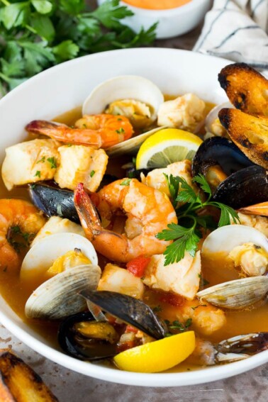 A serving bowl of bouillabaisse with shrimp, clams and fish.