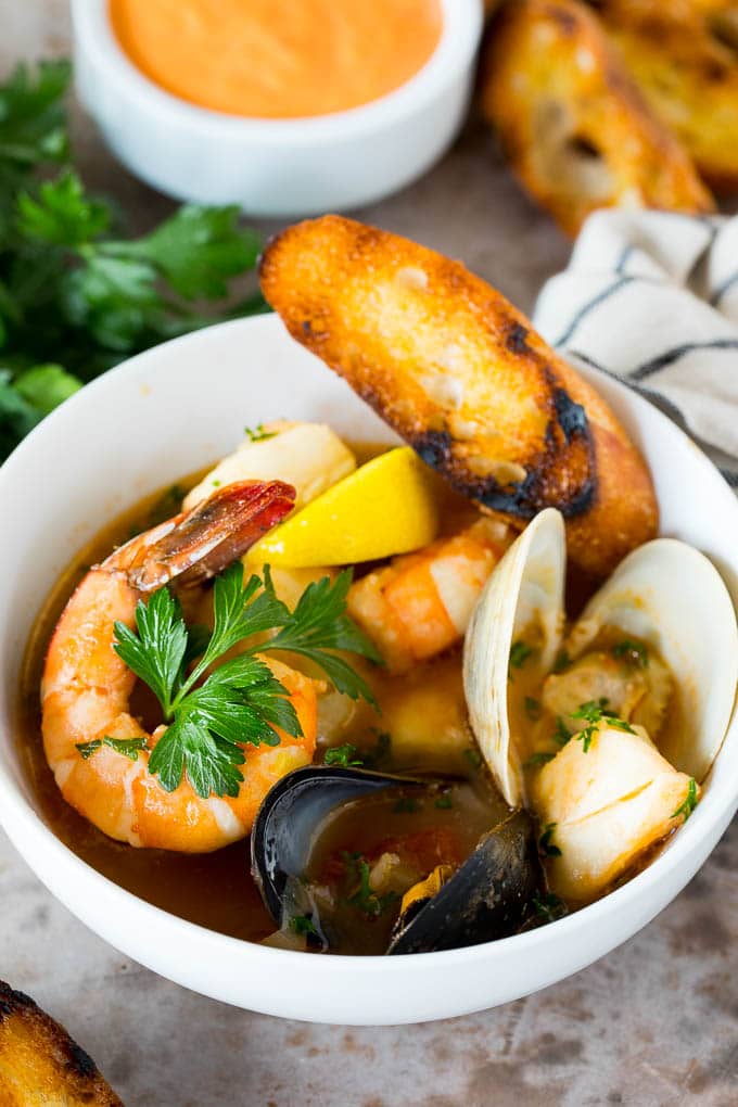 A bowl of bouillabaisse served with toasted bread slices.