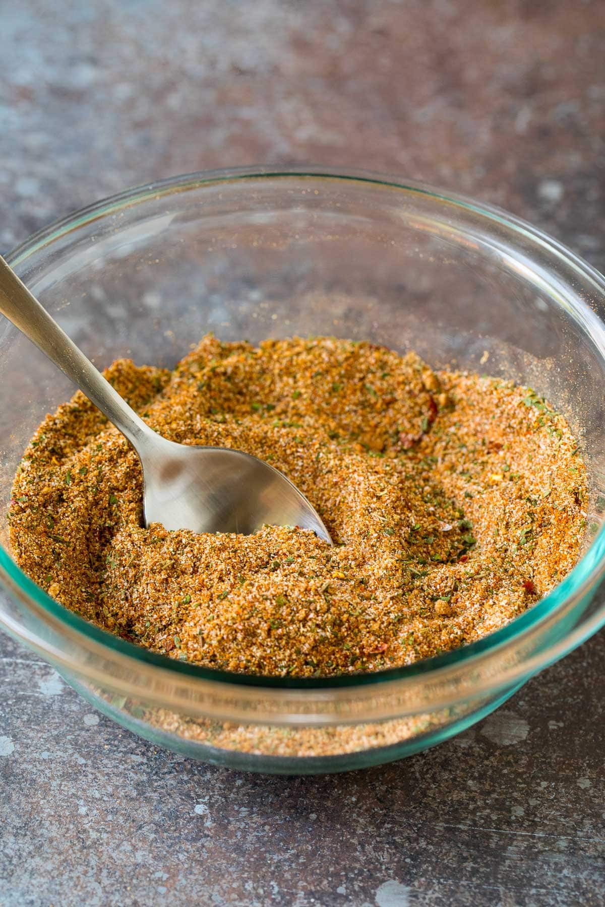 A bowl of spice mix with a spoon in it.