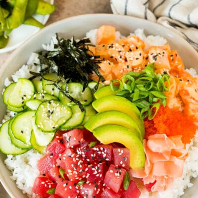 A sushi bowl topped with salmon, ahi, avocado, cucumber and nori.