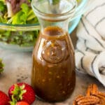 A bottle of balsamic vinaigrette surrounded by salad ingredients.