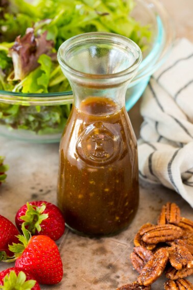 A bottle of balsamic vinaigrette surrounded by salad ingredients.