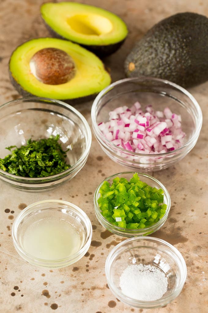 Bowls of ingredients including lime juice, cilantro, jalapeno and onions.