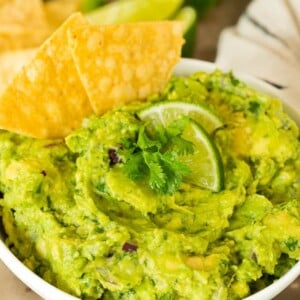 A bowl of Chipotle guacamole with chips.