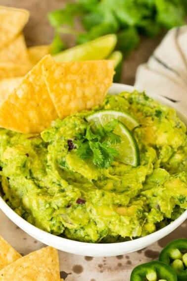 A bowl of Chipotle guacamole with chips.