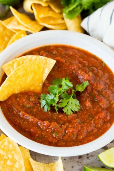 A bowl of chipotle salsa topped with fresh cilantro and tortilla chips.