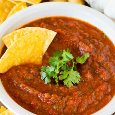 A bowl of chipotle salsa topped with fresh cilantro and tortilla chips.