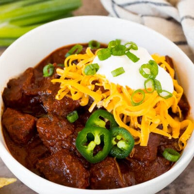 A bowl of Texas chili topped with cheese and sour cream.