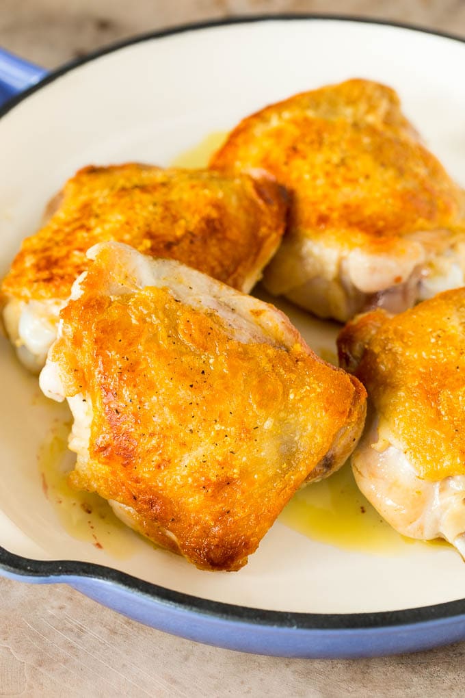 Browned chicken thighs in a pan.