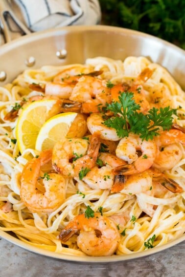 A pan of shrimp linguine garnished with lemon and parsley.