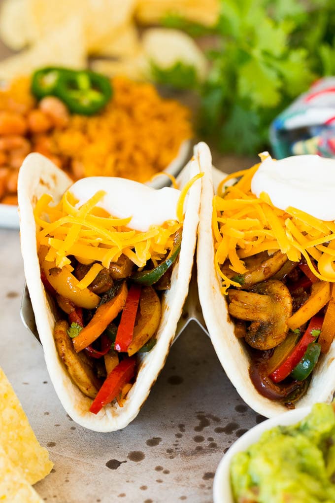 Two vegetarian fajitas topped with cheese and sour cream.