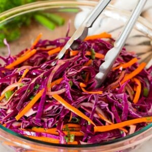 Tongs serving up a portion of red cabbage slaw.