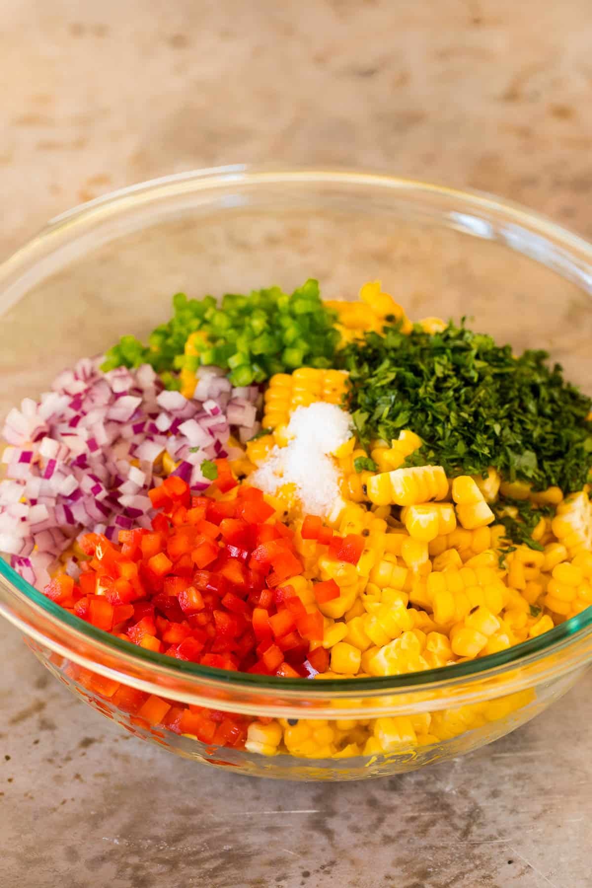 A bowl of corn with peppers, onions, cilantro and salt.