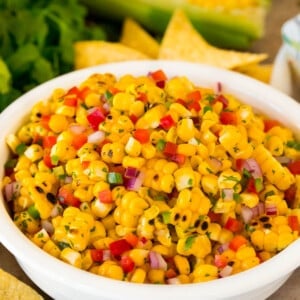 A bowl of corn salsa surrounded by tortilla chips.