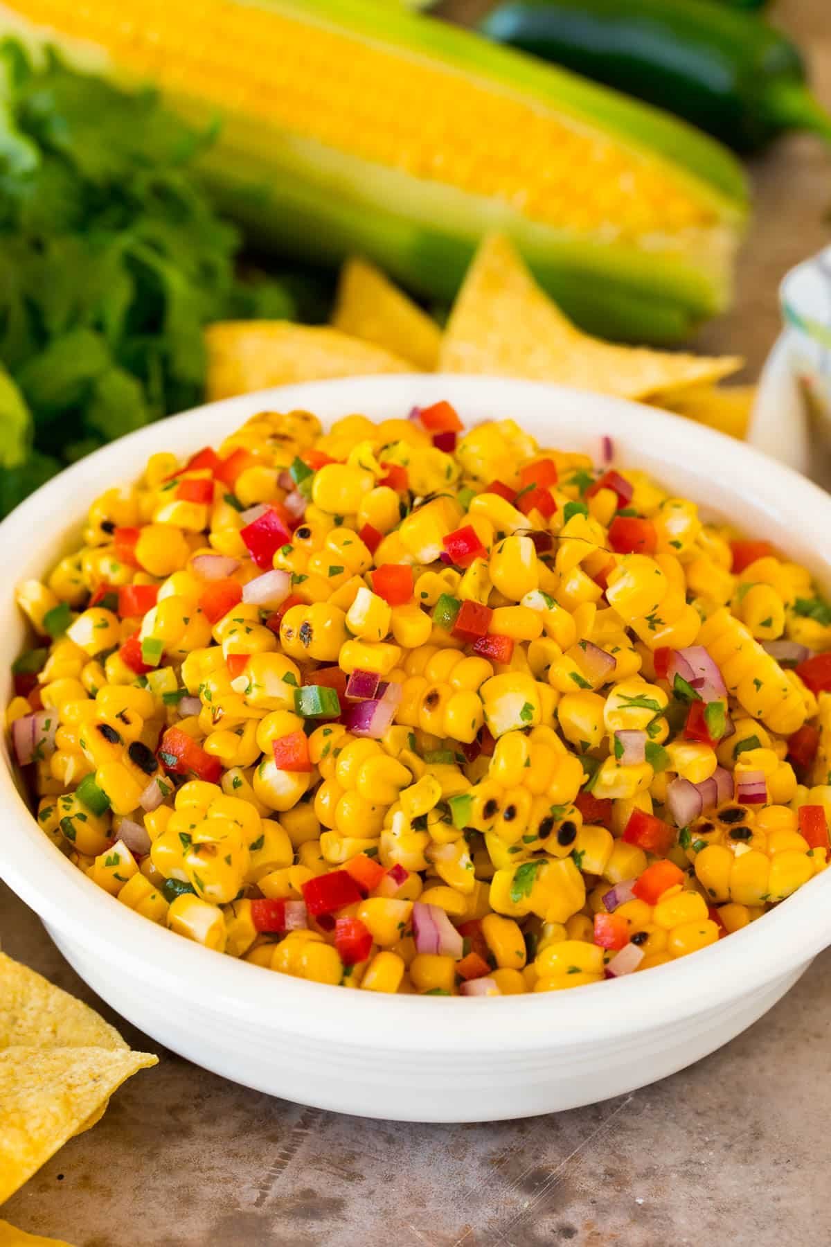 A bowl of corn salsa surrounded by tortilla chips.