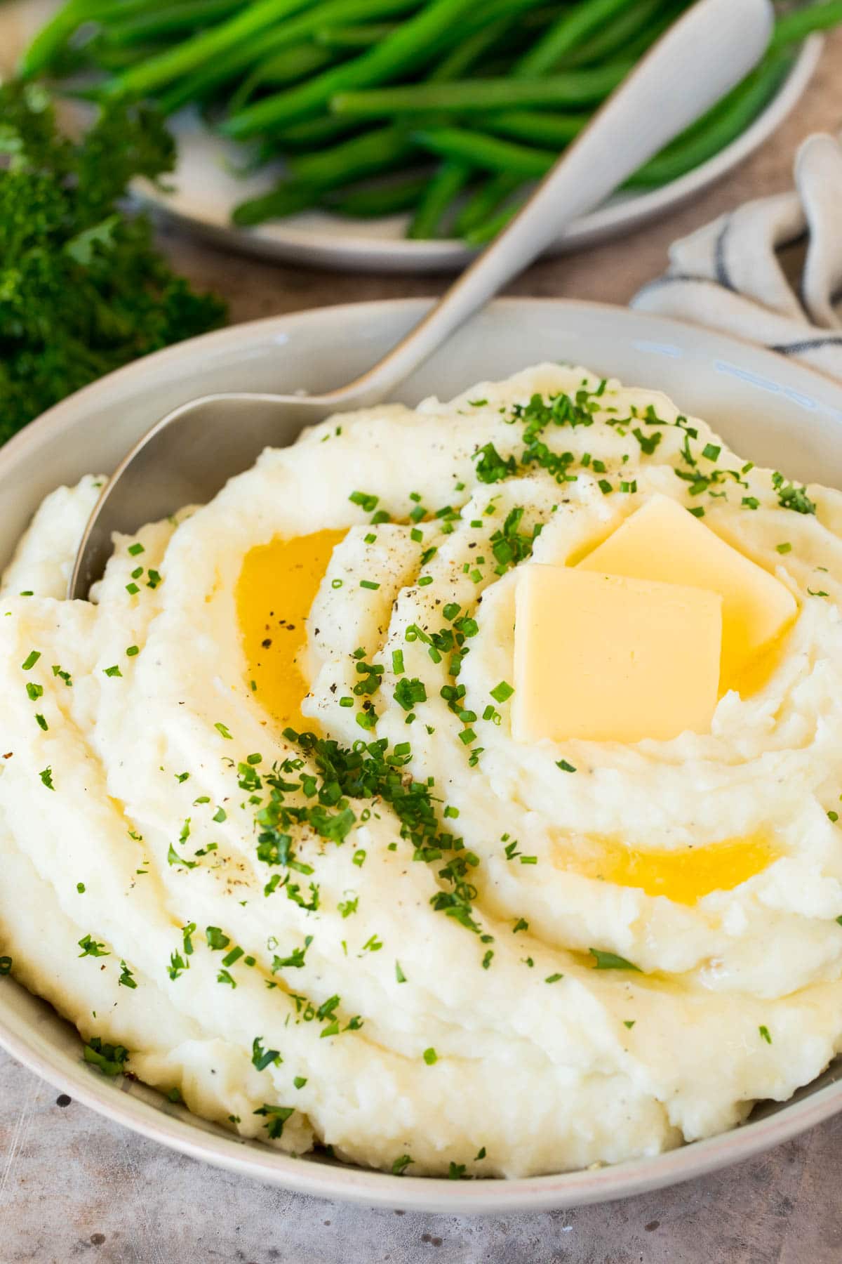 A bowl of make ahead mashed potatoes topped with butter and herbs.