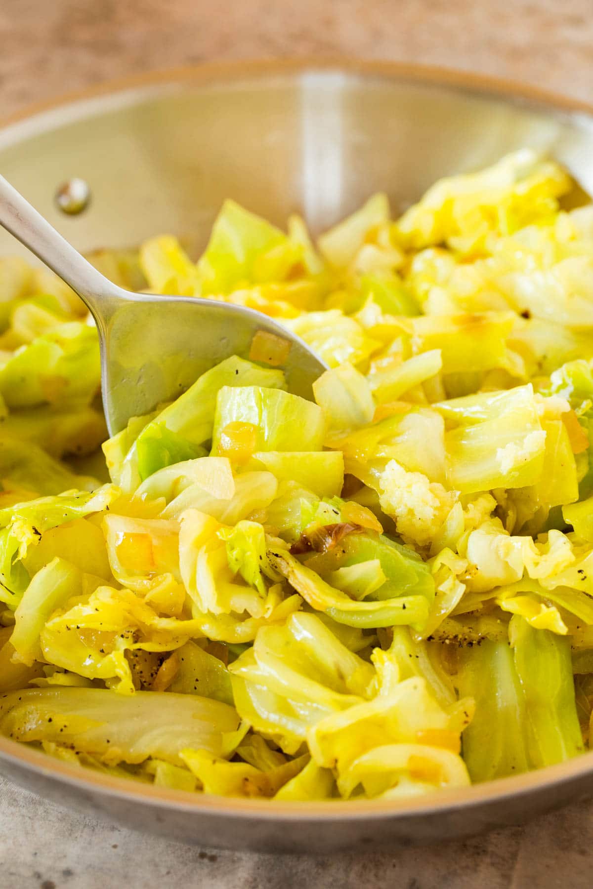 A pan of cooked cabbage with a spoon in it.