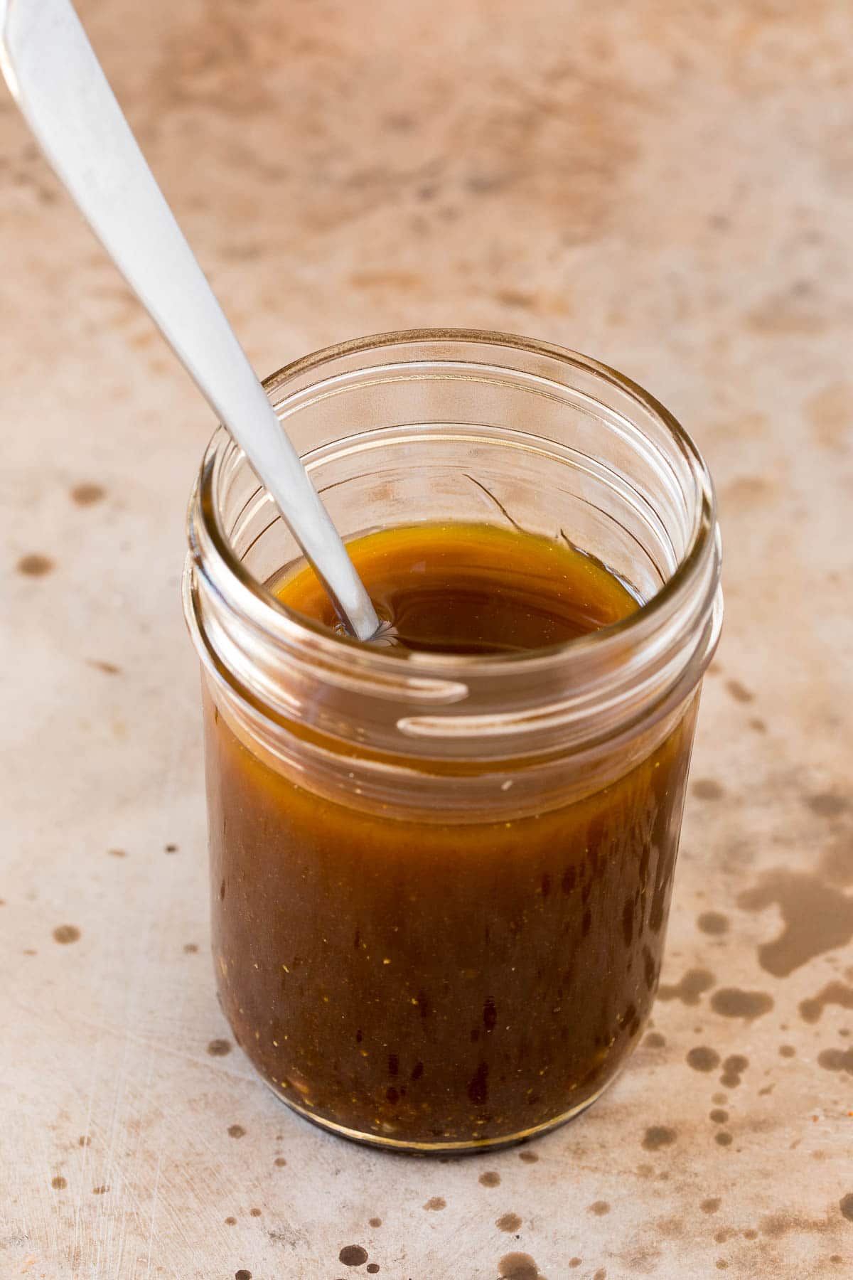 A jar of salad dressing with a spoon in it.