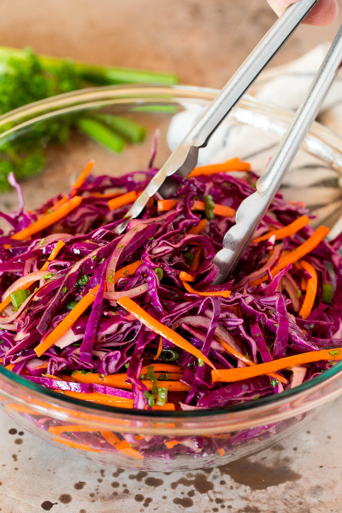 Tongs serving a portion of red cabbage slaw.
