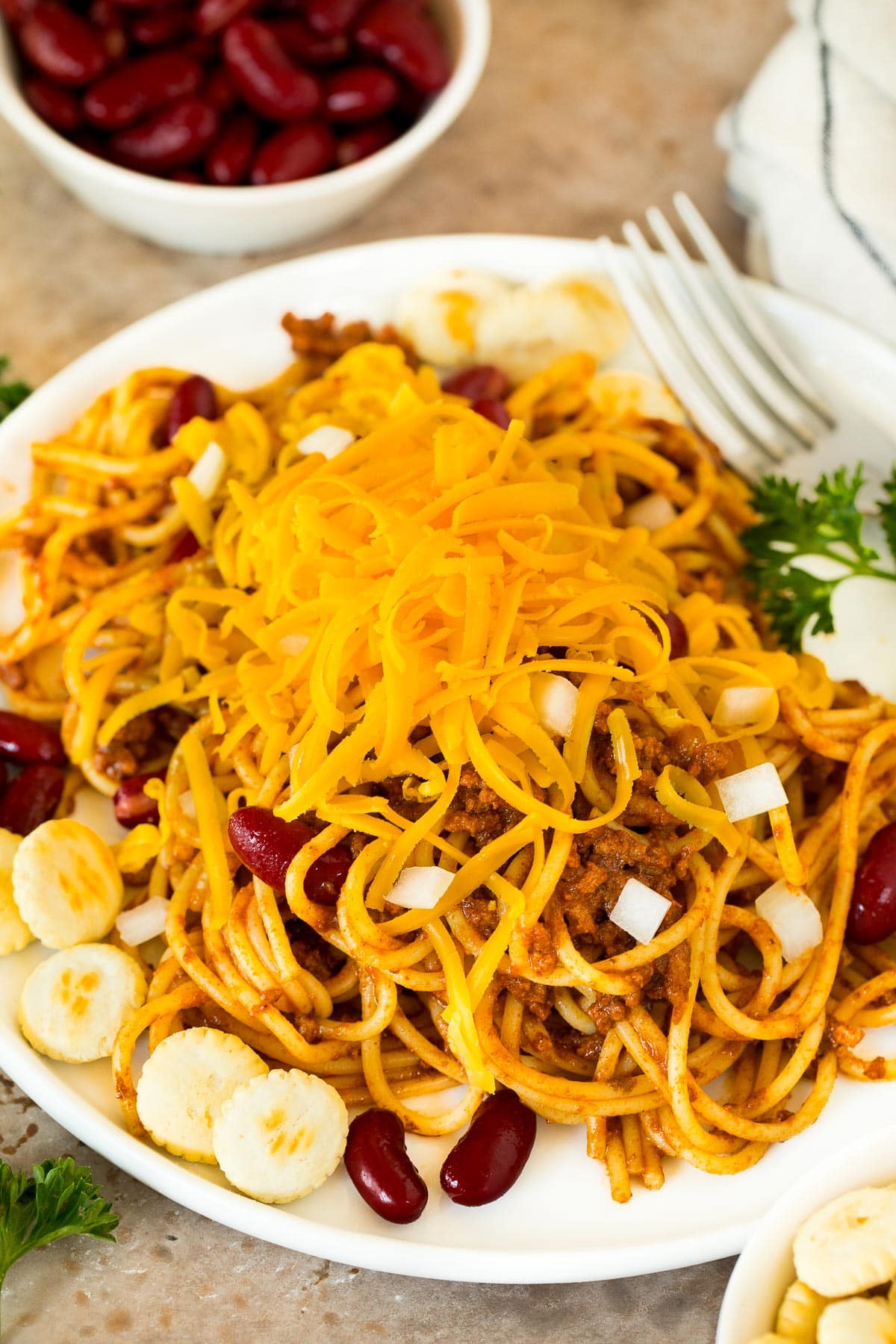 A plate of spaghetti tossed with Cincinnati chili and served with beans, oyster crackers and cheese.