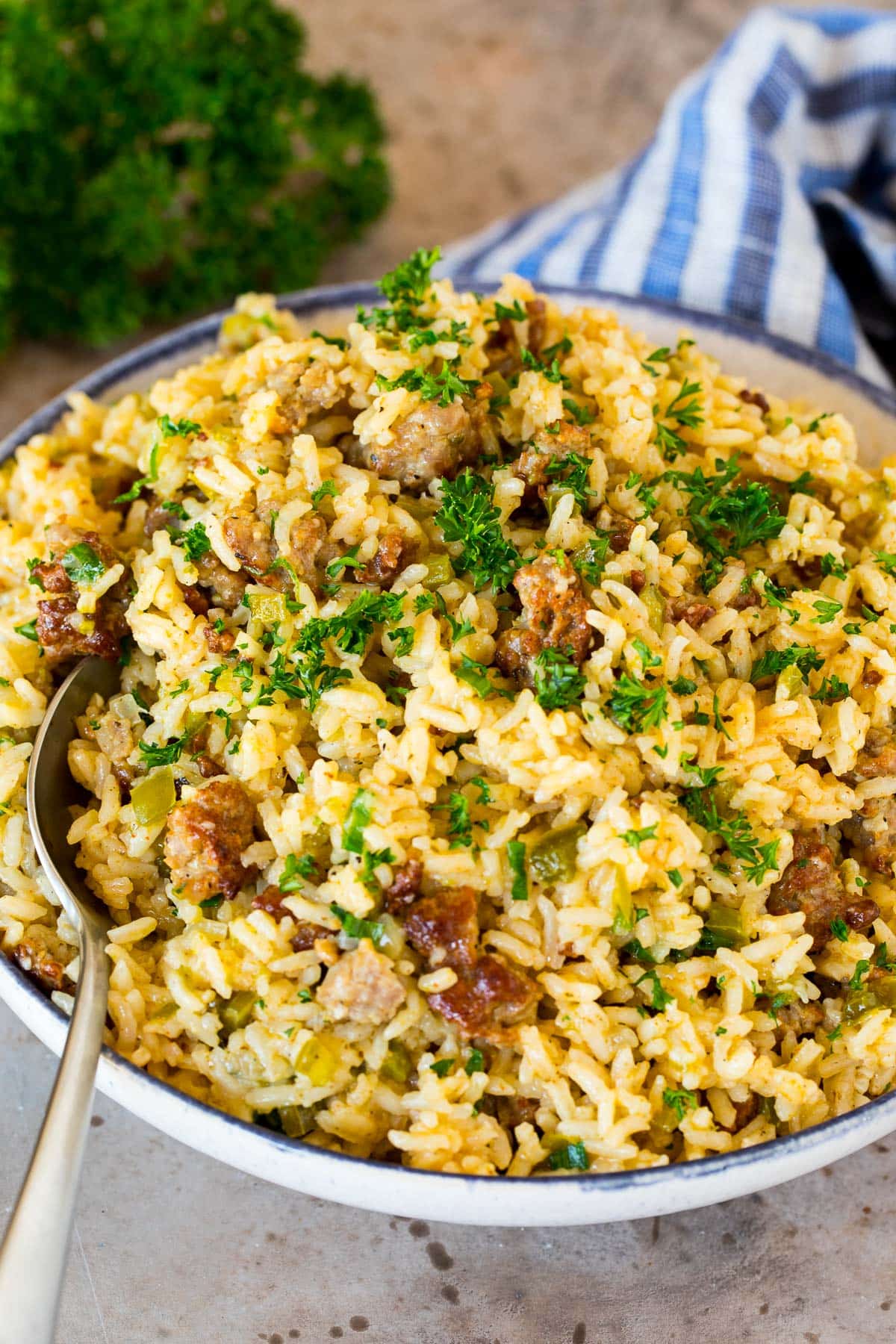 A bowl of dirty rice with a serving spoon in it.