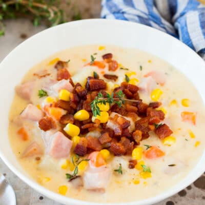 A bowl of ham and corn chowder garnished with bacon.
