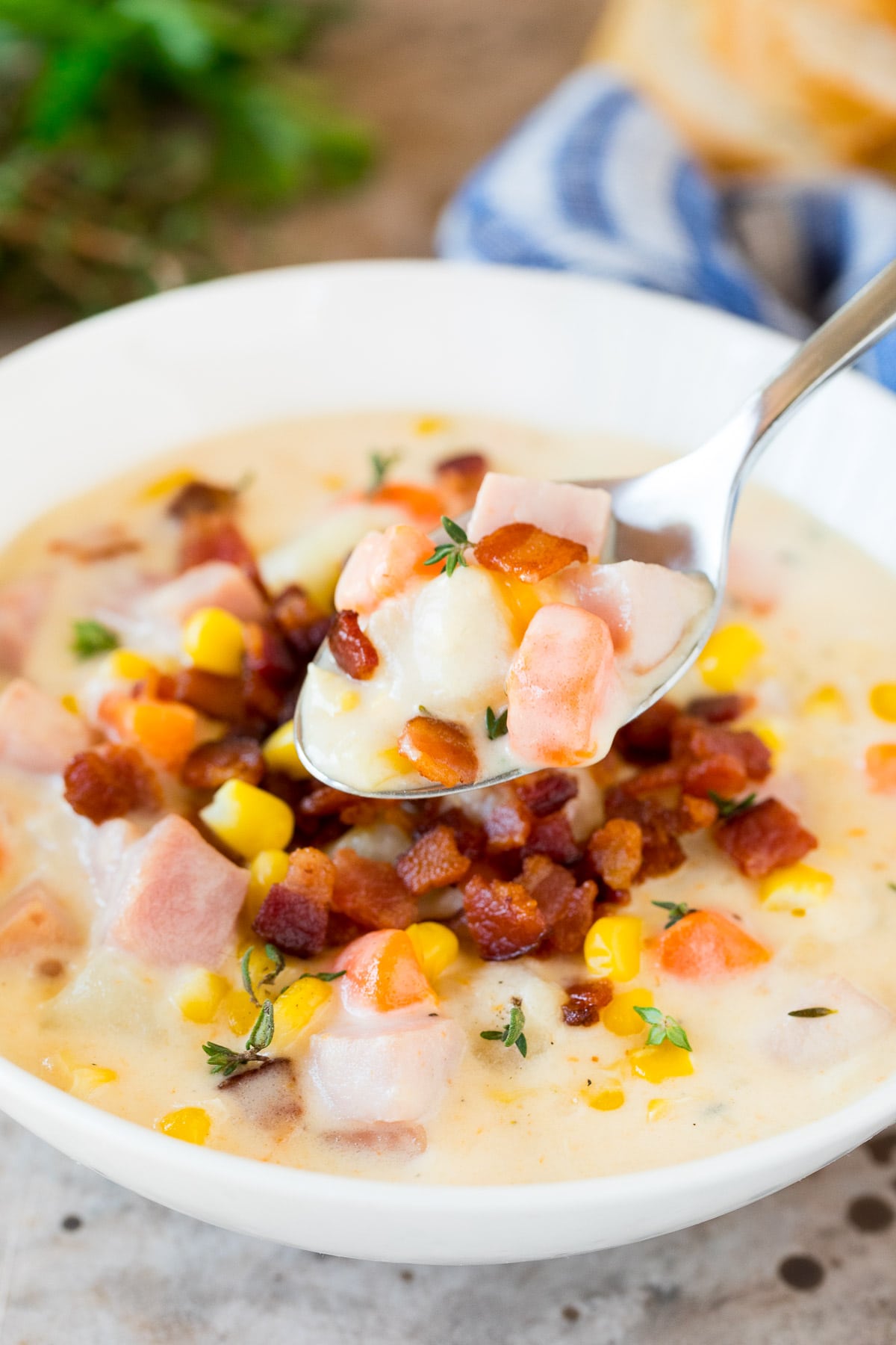 A spoon serving a portion of ham and corn chowder.