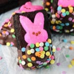 Brownies with pink bunny peeps on top half covered in chocolate.