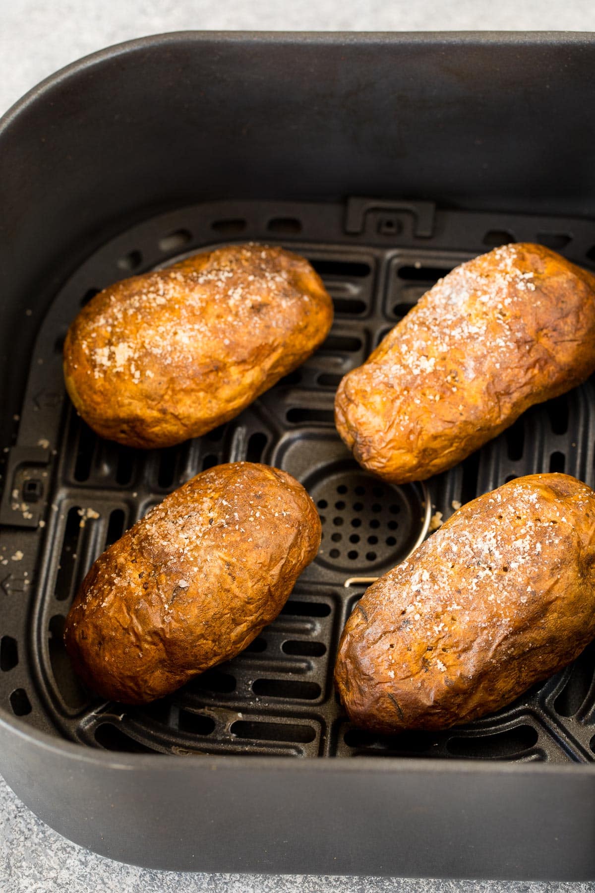 Cooked potatoes in the basket of an air fryer.
