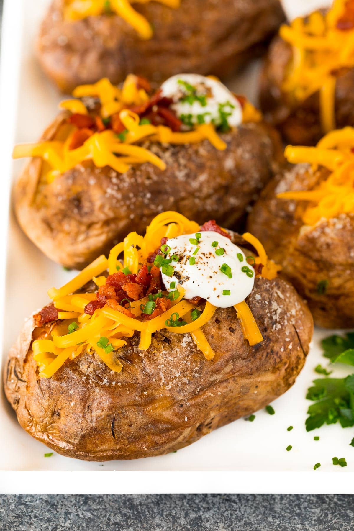 A platter of air fryer baked potatoes topped with cheese and bacon.