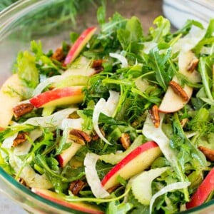 A bowl of fennel salad made with arugula, apples and pecans.