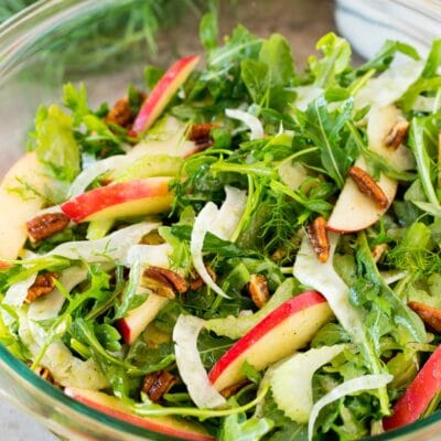 A bowl of fennel salad made with arugula, apples and pecans.